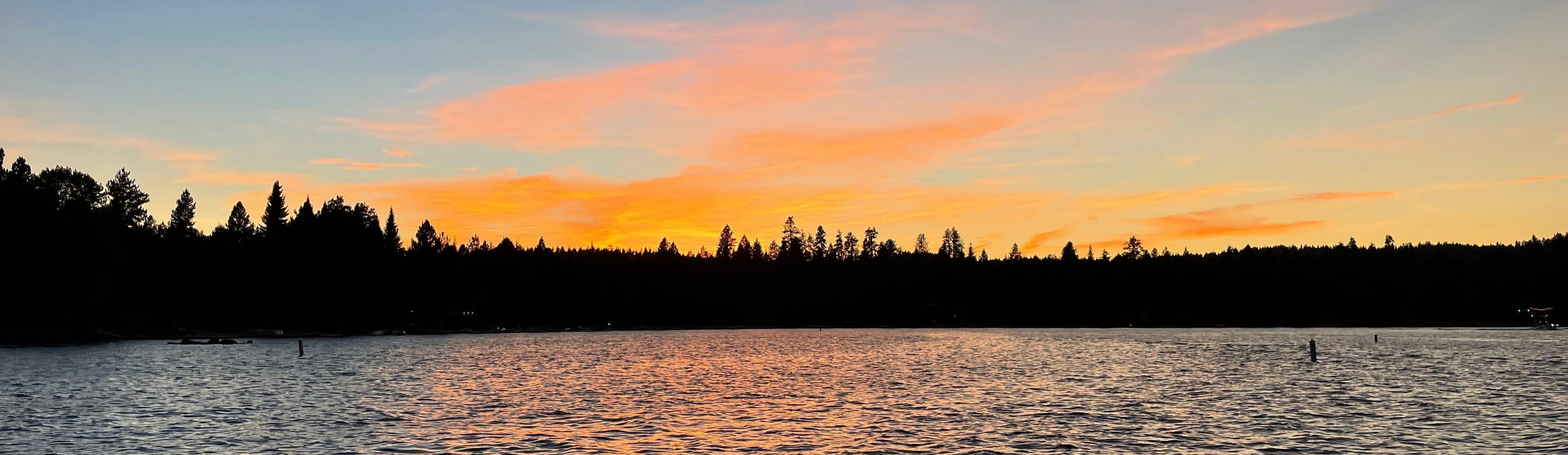 Sunset over a lake with silhouetted trees on the horizon